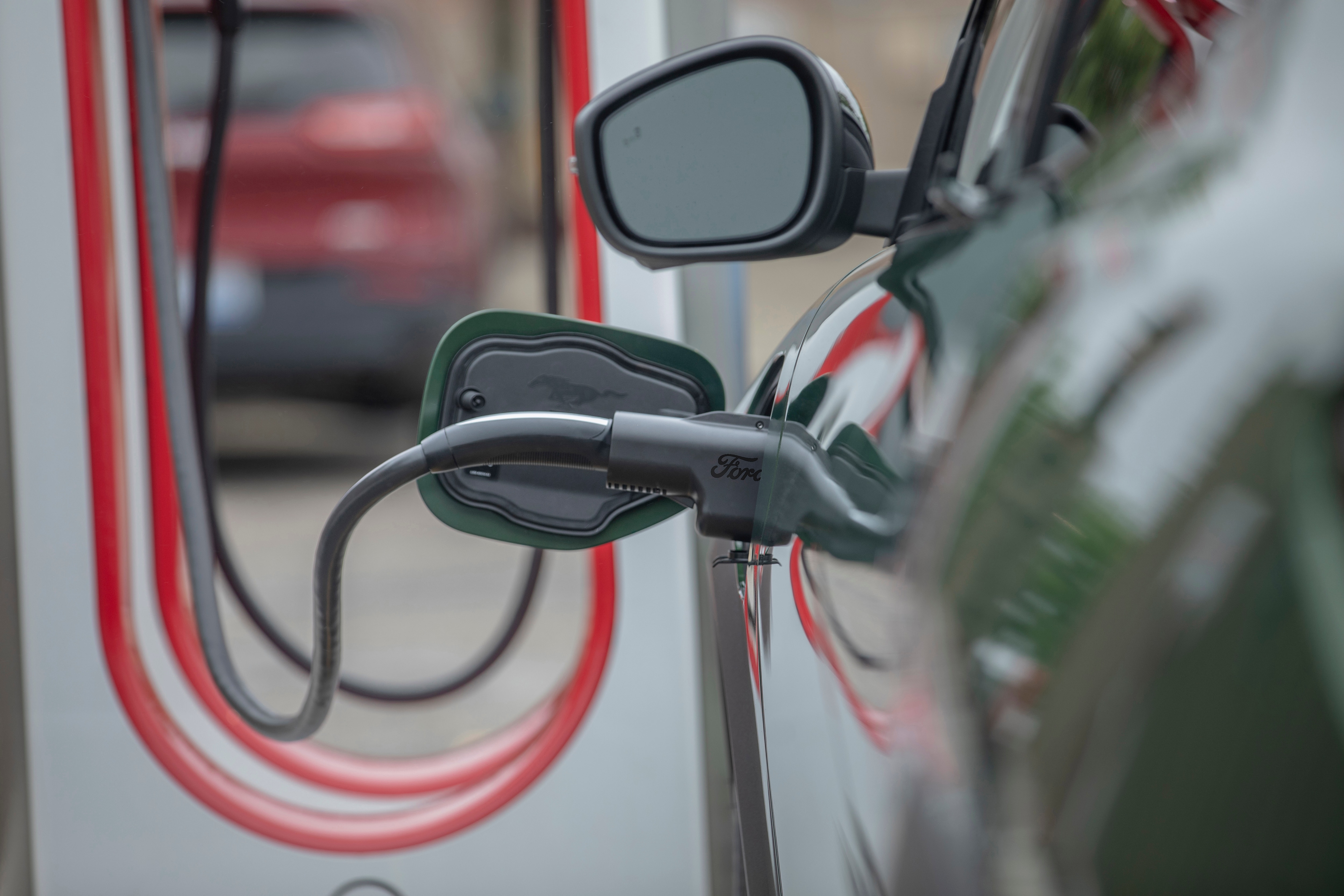 A Ford charging adapter is shown plugged into an electric vehicle.